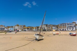 A beach with a sailboat, buildings, and a clear sky. - 3 Bed in St. Ives (oc-d42669) (St Ives)