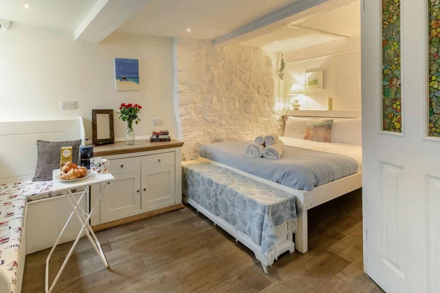 A cozy bedroom with a bed, bedside table, and a small desk with a chair.