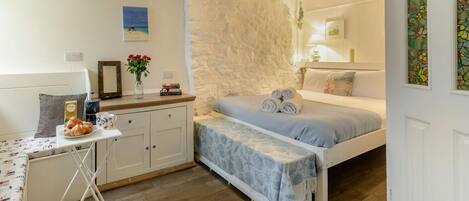 A cozy bedroom with a bed, bedside table, and a small desk with a chair.