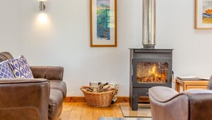 A cozy living room with a fireplace, a sofa, a coffee table, and a framed painting on the wall. - 2 Bed in Cotmore (oc-a44749) (Beeson)