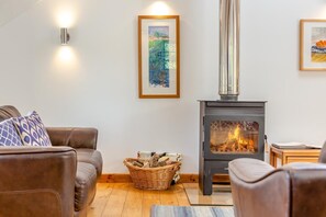 A cozy living room with a fireplace, a sofa, a coffee table, and a framed painting on the wall. - 2 Bed in Cotmore (oc-a44749) (Beeson)