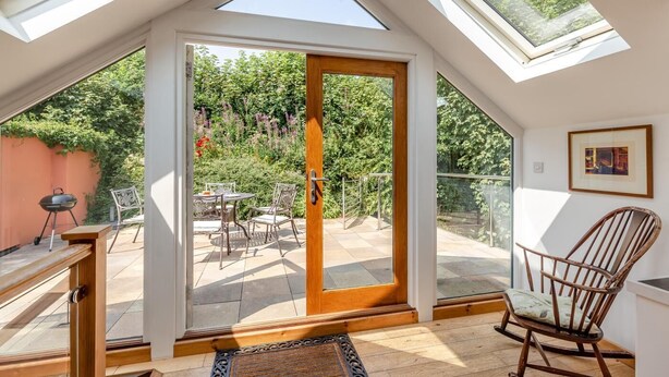 A room with a skylight, a sliding glass door leading to an outdoor patio, and a chair. - 2 Bed in Cotmore (oc-a44749) (Beeson)