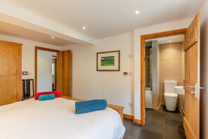 Un dormitorio con una cama grande, un armario de madera, un espejo y un baño con inodoro y lavamanos.