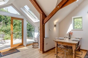 Un comedor con mesa de madera, sillas y vistas al jardín a través de amplios ventanales.