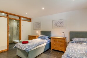A bedroom with two beds, a wooden wardrobe, a bedside table with a lamp, and a glass shower enclosure. - 2 Bed in Cotmore (oc-a44749) (Beeson)