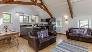A spacious loft with a kitchen, two leather sofas, and a dining area. - 2 Bed in Cotmore (oc-a44749) (Beeson)