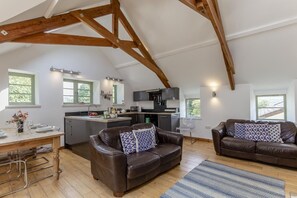 A spacious loft with a kitchen, two leather sofas, and a dining area. - 2 Bed in Cotmore (oc-a44749) (Beeson)