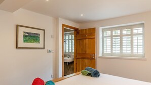 A bedroom with a bed, a window with blinds, a door leading to a bathroom, and a framed picture on the wall. - 2 Bed in Cotmore (oc-a44749) (Beeson)