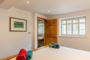 A bedroom with a bed, a window with blinds, a door leading to a bathroom, and a framed picture on the wall. - 2 Bed in Cotmore (oc-a44749) (Beeson)
