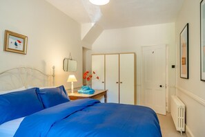 Une chambre à coucher comprenant un lit, une table de chevet, une lampe, un miroir, une armoire et un radiateur.