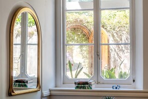 A room with a large arched window, a mirror, and a shelf with books and a camera. - 2 Bed in Niton Undercliff (oc-60945) (Niton)