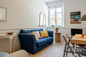 A living room with a blue sofa, a small round table, a TV, and a painting on the wall. - 2 Bed in Niton Undercliff (oc-60945) (Niton)