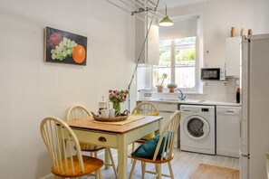 Une cuisine compacte comprenant un coin repas, un lave-linge et un four à micro-ondes.