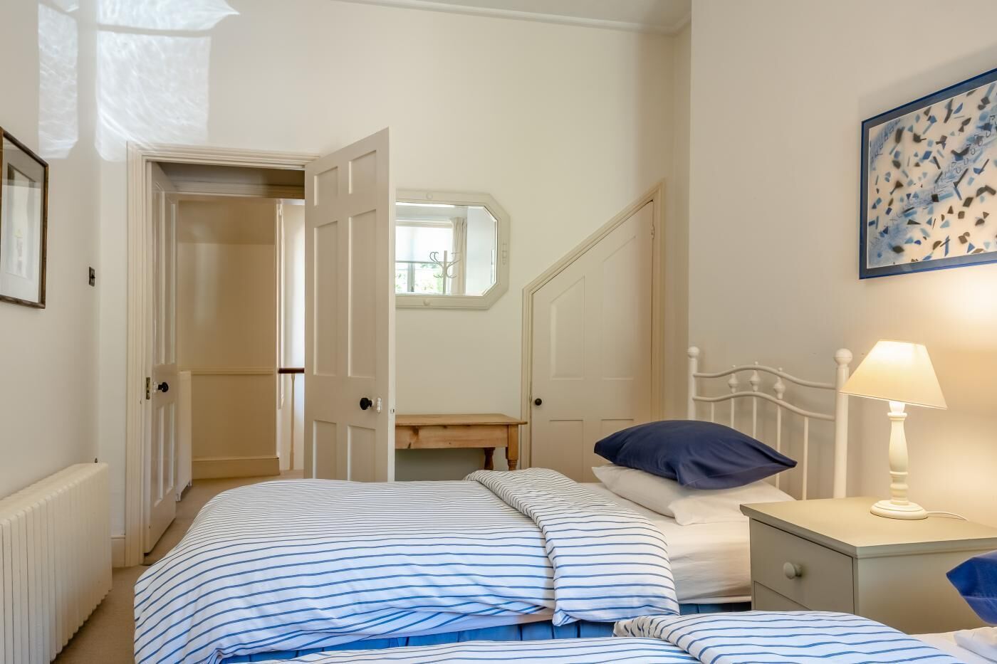 A bedroom with a bed, bedside table, lamp, and a window with a view.