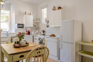 A kitchen with white cabinets, a microwave, a stove, and a refrigerator. - 2 Bed in Niton Undercliff (oc-60945) (Niton)