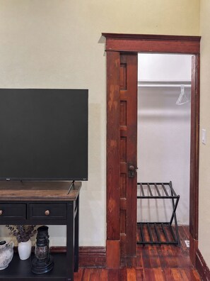 Ein Zimmer mit Holztür, einem Fernseher auf einem Holzgestell und einem kleinen Tisch mit Dekoration.