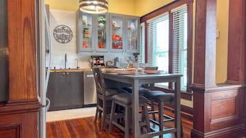Una cocina con una mesa y sillas de madera, una lámpara colgante y una ventana con persianas.