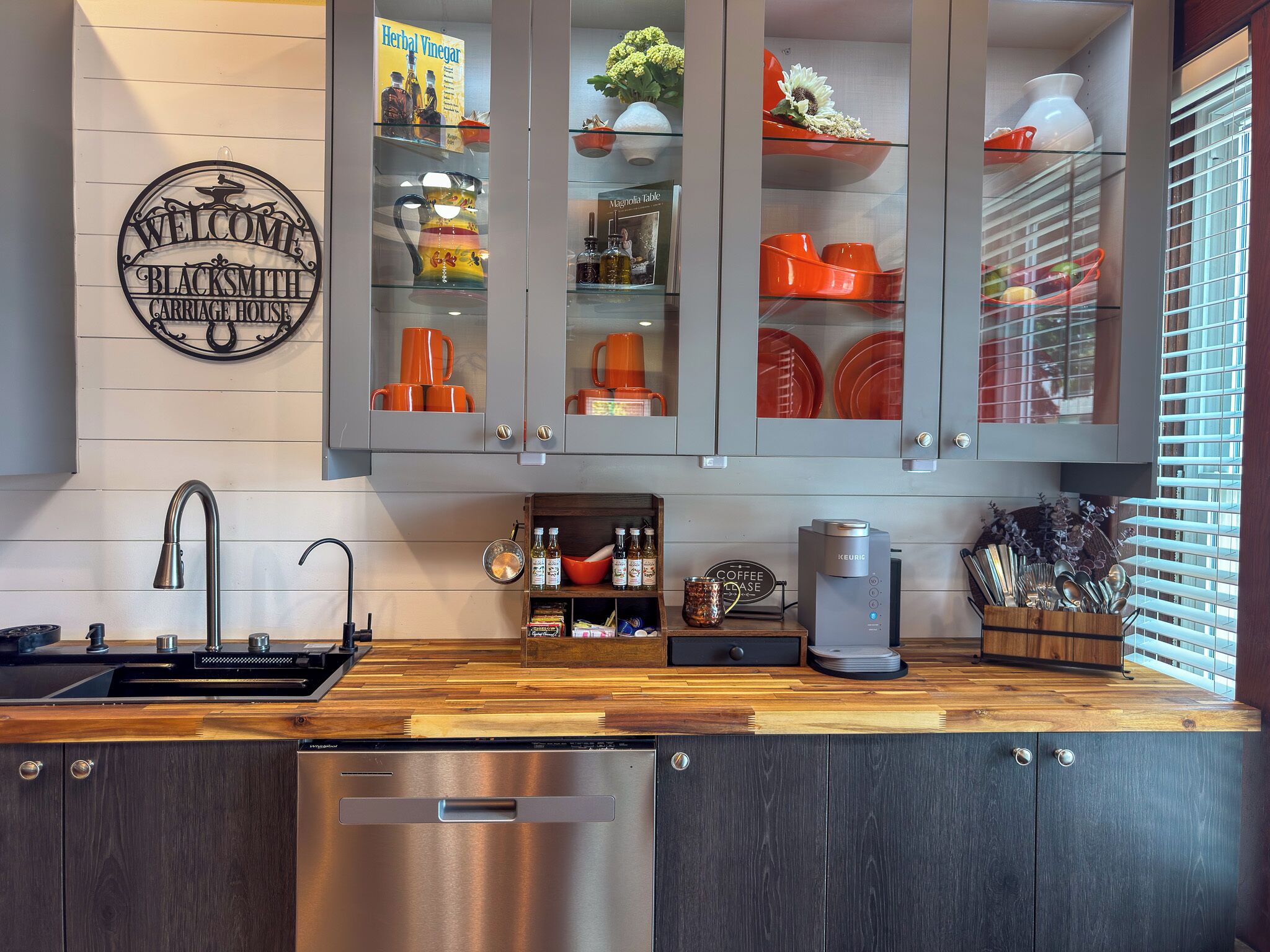 A kitchen with a stainless steel dishwasher, a coffee machine, and a wooden countertop.