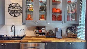 A kitchen with a stainless steel dishwasher, a coffee machine, and a wooden countertop.