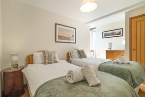 A hotel room with two beds, a bedside table, a mirror, and a wooden wardrobe. - 3 Bed in Crickhowell (oc-tyobr) (Cwmdu)