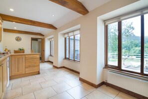 Una cocina amplia con armarios de madera, una isla central y grandes ventanales con vistas al exterior.
