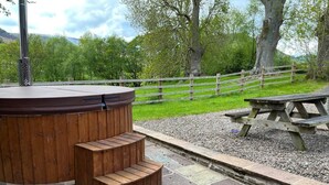 Een hottub met houten trap en een picknicktafel in een park.