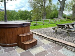 Ein Whirlpool mit Holzstufen und einem Picknicktisch inmitten einer Parkanlage.