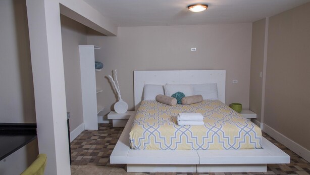 A bedroom with a bed, a bedside table, a lamp, and a wall socket. - Oceanfront Escape Breathtaking Sea Views (San Antonio del Mar)