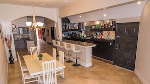 Une cuisine moderne avec un coin bar, des tabourets de bar blancs et une table à manger avec des chaises.