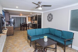 Una sala de estar con un sofá color turquesa, una mesa de centro y un comedor con sillas y una mesa.