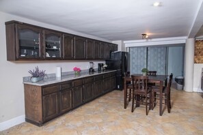 Una cocina con gabinetes de madera oscura, encimera de granito y un comedor con mesa y sillas.