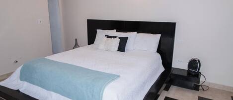 A bed with a black headboard, white bedding, and a blue throw blanket.