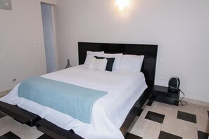 Un letto con testiera nera, biancheria da letto bianca e una coperta azzurra.