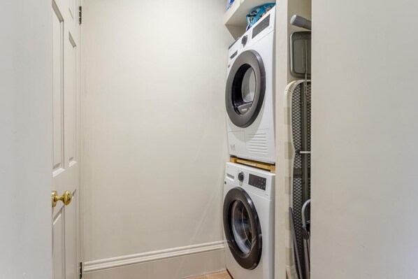 A laundry room with two stacked front-loading washing machines and a dryer.