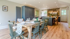 A modern kitchen with a dining area, wooden flooring, and a stone backsplash. - 4 Bed in Ardvasar (oc-r43279) (Ardvasar)