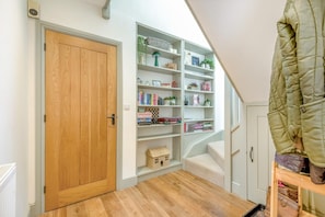 Ein Zimmer mit Holztür, Bücherregal, Garderobe und einer Treppe.
