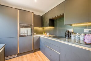 Eine moderne Küche mit Einbauofen, Kaffeemaschine und Wasserkocher auf der Arbeitsfläche.