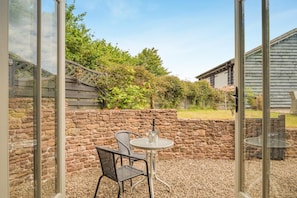 Eine Terrasse im Freien mit Steinmauern, einem Tisch und zwei Stühlen.