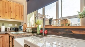 A kitchen with wooden cabinets, a sink, and a window with a view of houses. - 2 Bed in Partney (oc-v44757) (Partney)