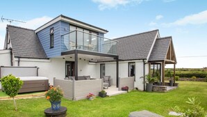 A modern house with a glass conservatory, a hot tub, and a well-maintained lawn. - 3 Bed in Bryngwran (oc-y44816) (Bodedern)