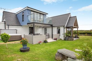 Ein modernes Haus mit Wintergarten, Whirlpool und gepflegtem Rasen.