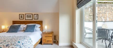 Een slaapkamer met een bed, nachtkastjes, een raam met uitzicht en lijstjes met afbeeldingen aan de muur.