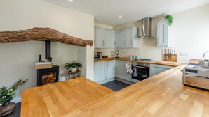 Een moderne keuken met een centraal eiland, inbouwapparatuur en een rustieke houten balk.