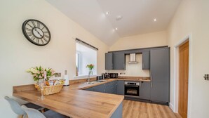 A modern kitchen with a central island, grey cabinets, and a wooden countertop. - 2 Bed in Kirkmahoe (oc-h44227) (Dumfries)