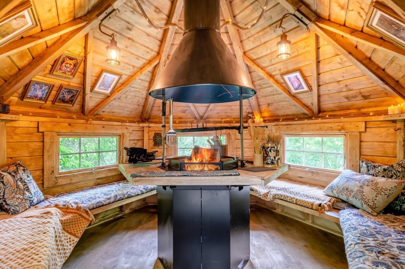 Een gezellig houten chaletinterieur met een houtkachel in het midden, houten wanden en een schuine kap.