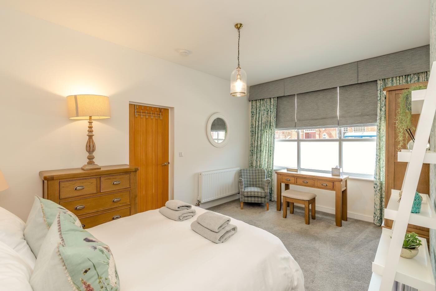 A bedroom with a bed, a wooden dresser, a desk, and a chair.