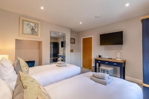 Ein Hotelzimmer mit zwei Betten, einem Schreibtisch, einem Spiegel, einem Fernseher und einem Kleiderschrank.