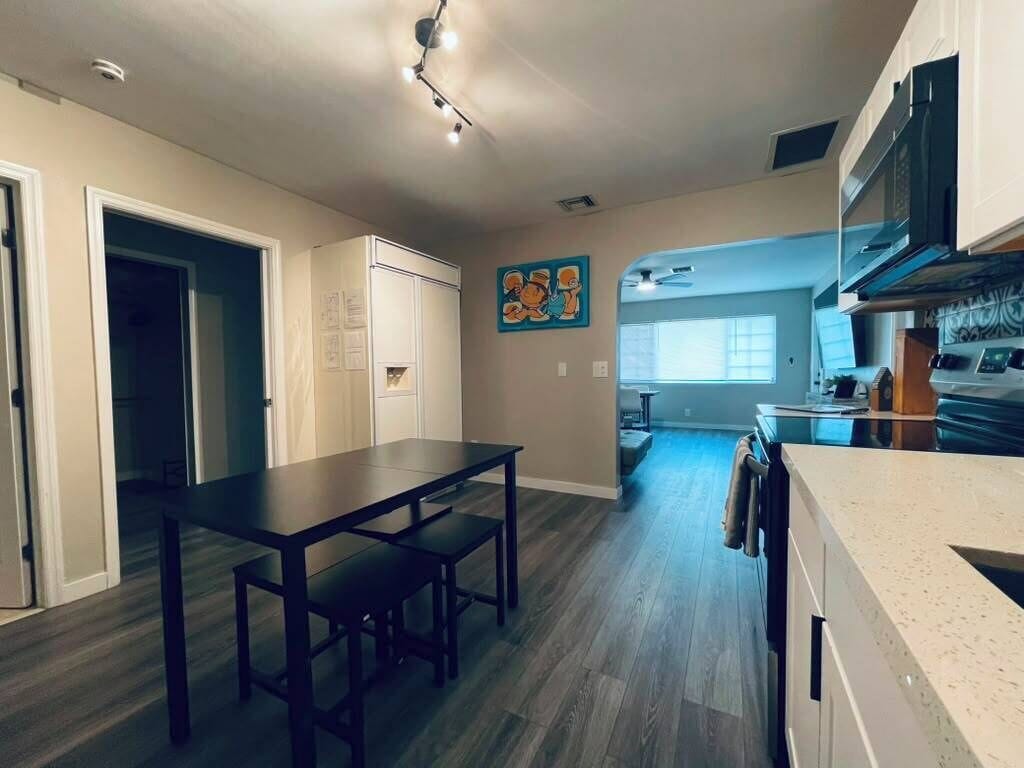 A modern kitchen with a dining area, a kitchen island, and a view into the living room.