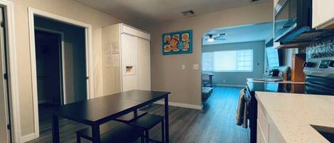 A modern kitchen with a dining area, a kitchen island, and a view into the living room.