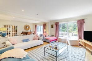 A spacious living room with a sofa set, a coffee table, and a television. - 4 Bed in Itchenor (oc-l45314) (Itchenor)